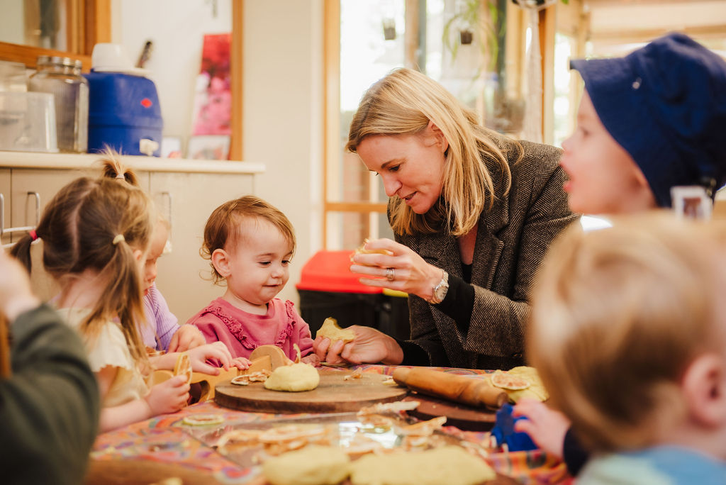 Educator with blonde hair showing baby with pink top some playdough