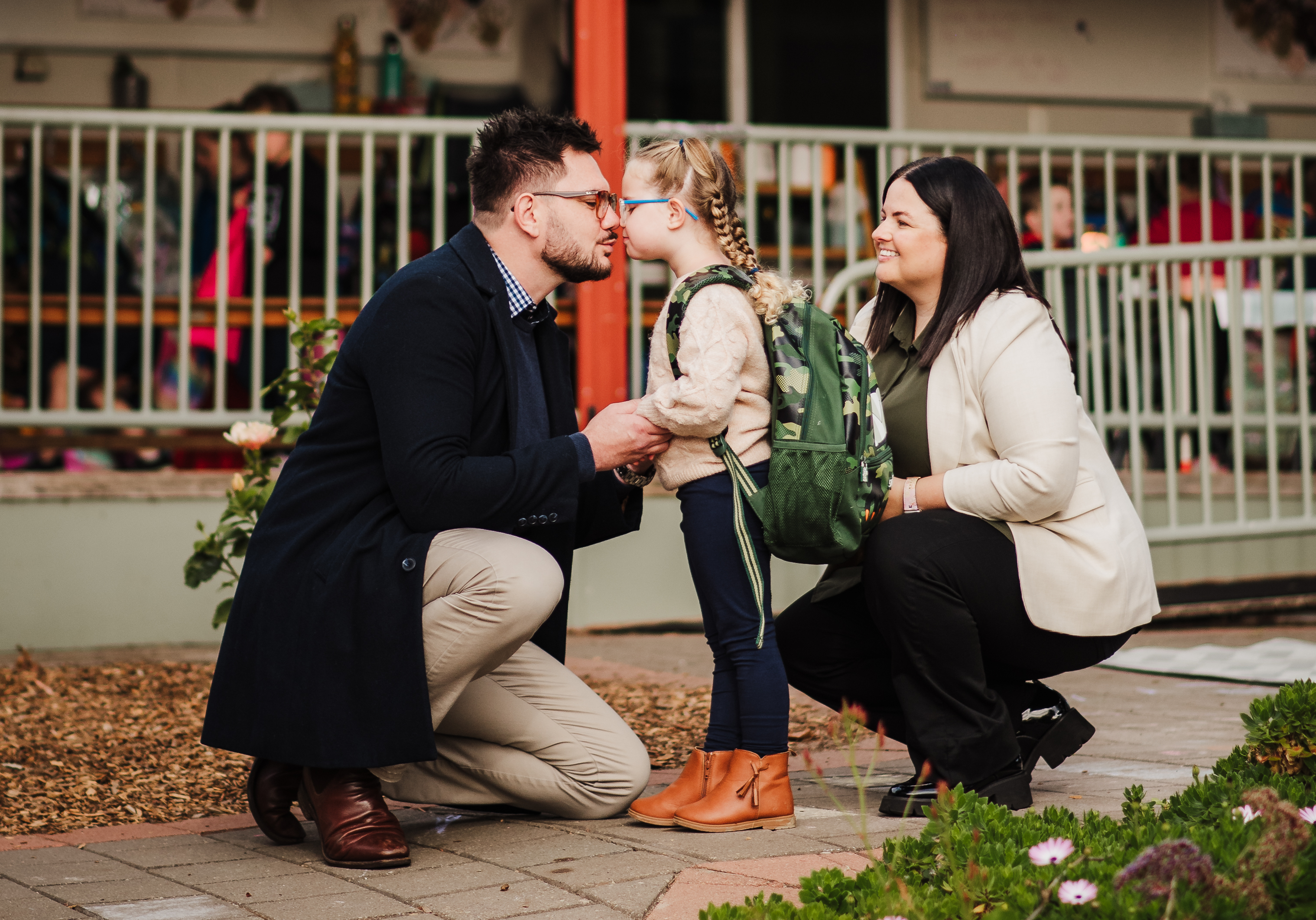 A dad and daughter share a special moment with mum watching on at kindy drop off