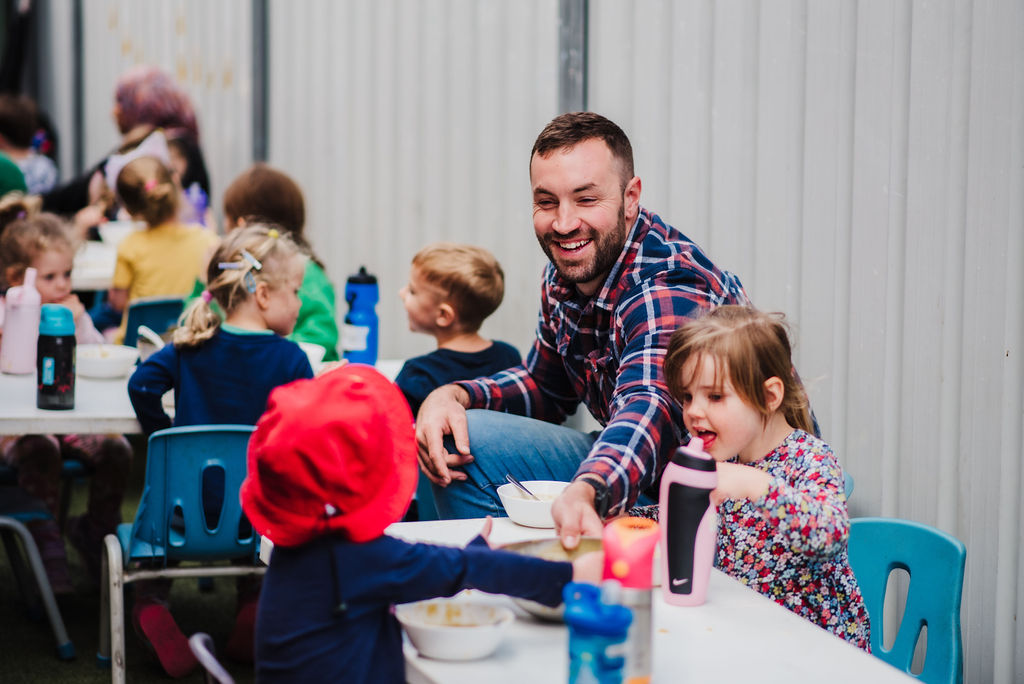 Educator with children passing bowl at lunch time