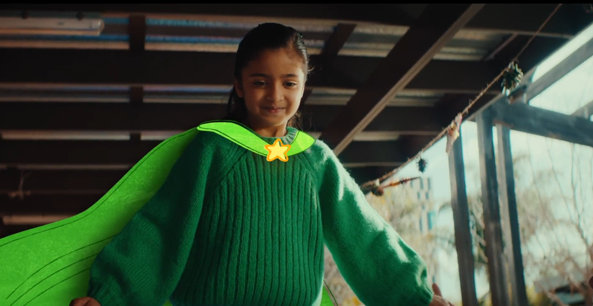 A young girl wearing an animated super hero cape preparing to take a leap