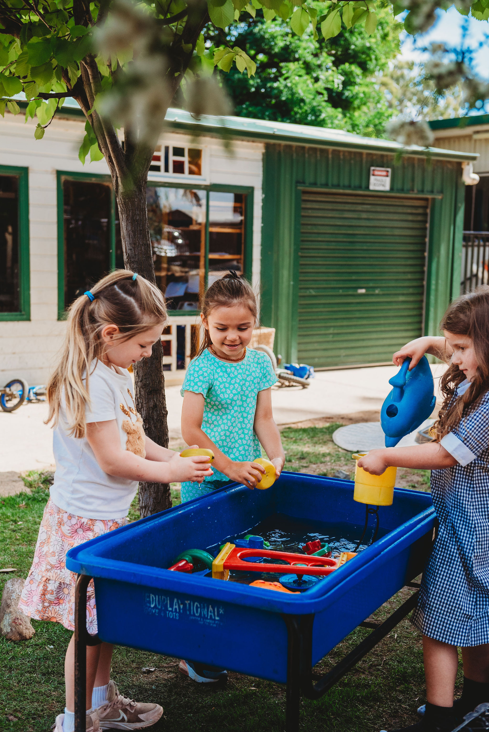 three children playing with toys in a bucket of water 